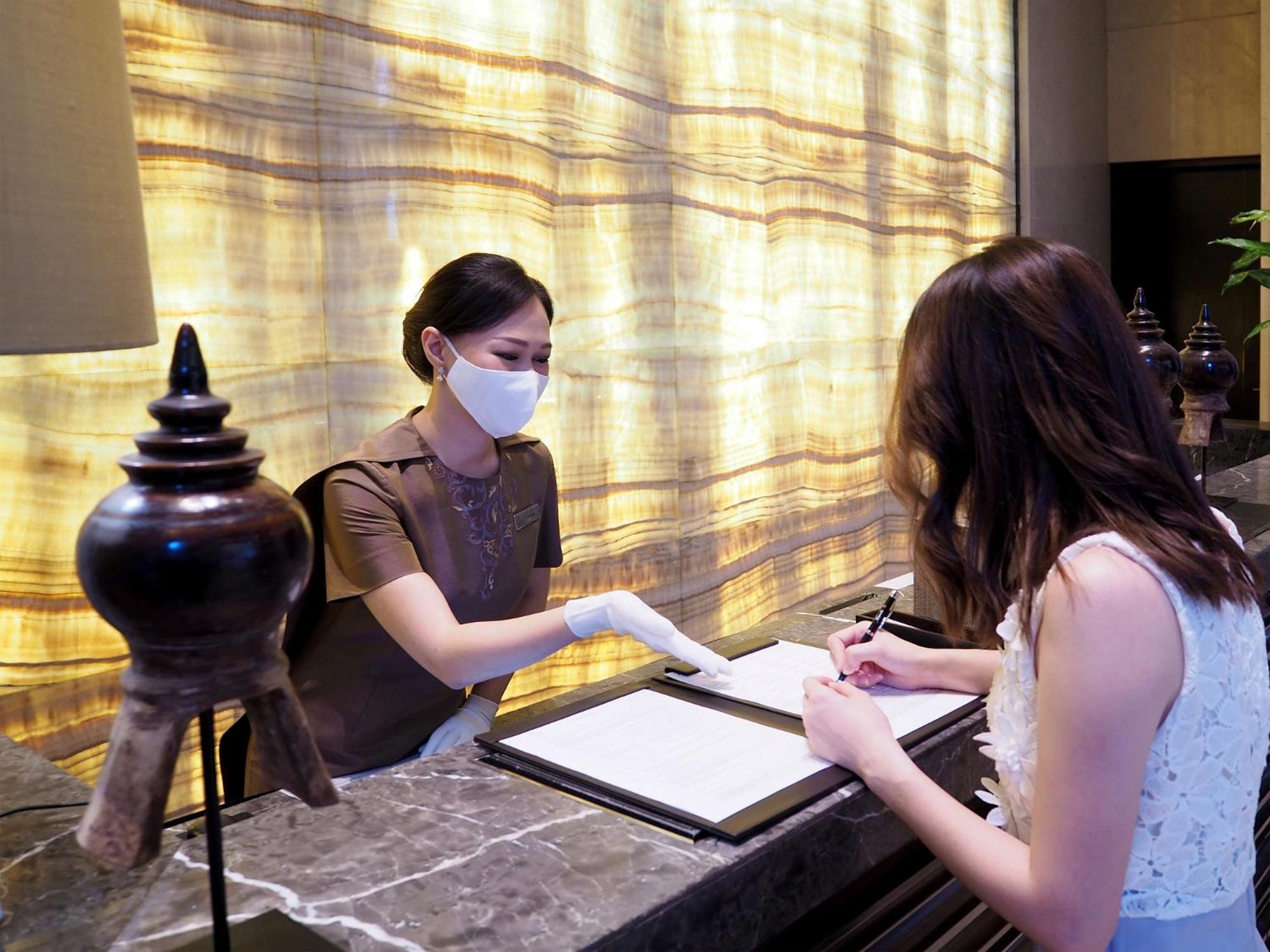 Siam Kempinski Hotel Bangkok Exterior foto A hotel receptionist wearing a face mask